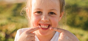 Little girl pointing to her smile