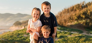 Three kids smiling outdoors