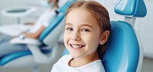 girl smiling in the dentist chair and enjoying the benefits of tooth-colored fillings