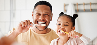dad and daughter brushing their teeth together