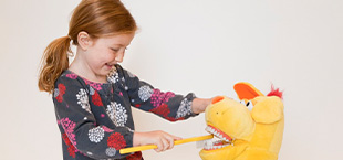 Little girl practicting tooth brushing on doll