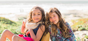 Two smiling teen girls at the beach