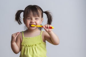 Happy little girl brushing her teeth. 