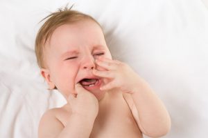 Crying baby experiencing tooth pain. 