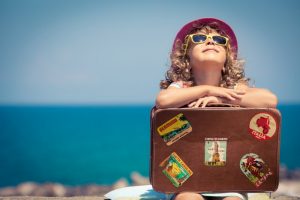 Child with suitcase, ready to travel. 