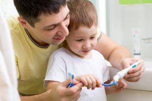 father and son brushing teeth