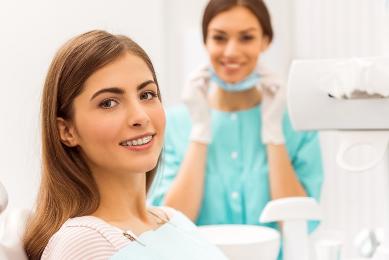 a teenage girl smiling while the dental hygienist smiles in the background
