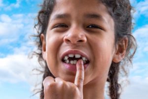 little girl outside pointing to her teeth