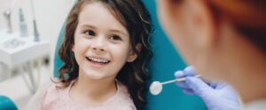 little girl with baby teeth smiling at the dentist